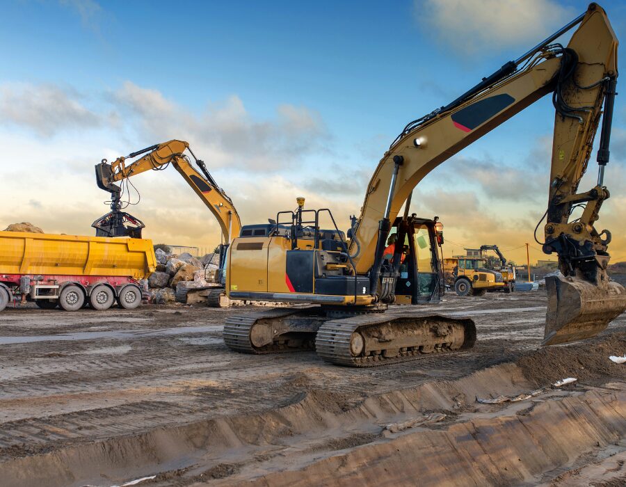 Excavatrice en train de charger des pierres dans une benne au coucher du soleil.