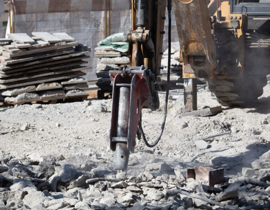 Hydraulic breaker crushing concrete at a construction site.