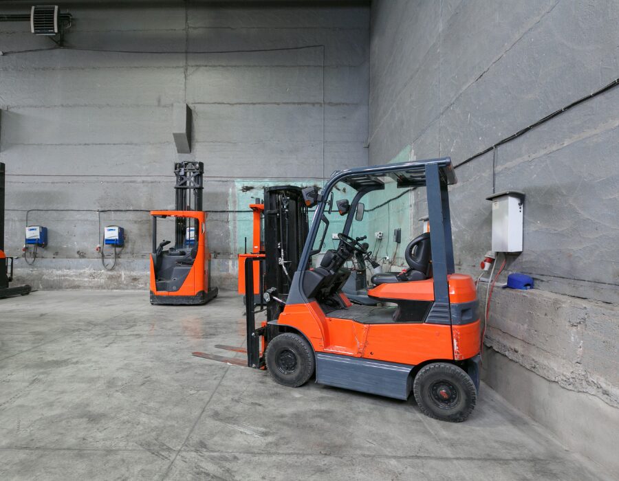 Elektrische Gabelstapler beim Aufladen in einer Lagerhalle aus Beton. 