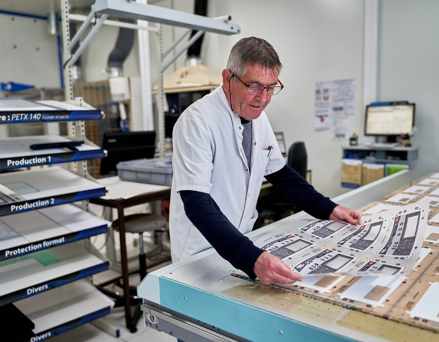 Worker inspecting printed panels in a manufacturing facility.