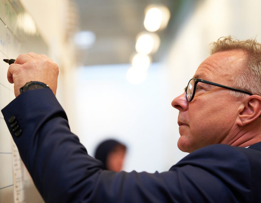 Homme écrivant sur un tableau blanc dans un bureau.