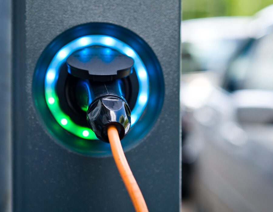 Electric vehicle charging at station with glowing LED lights. 