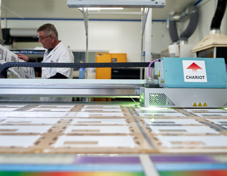 Technician overseeing a laser cutting machine in a workshop.